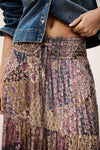 Person wearing a patterned skirt and denim jacket on a plain background