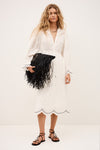 Woman in a white dress holding a black clutch against a white background from ba&sah