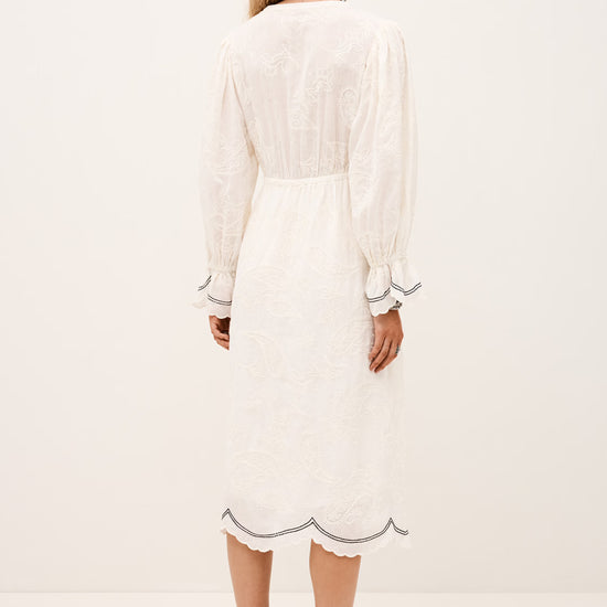 Woman wearing a white dress with long sleeves on a plain background rear view