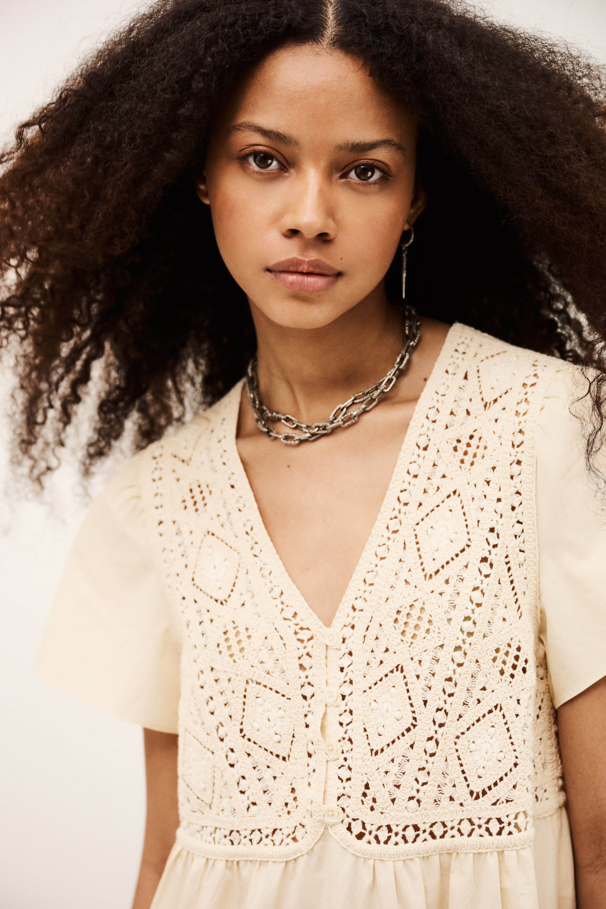 Woman wearing a beige lace top with a neutral background