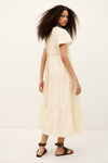 Woman wearing a cream-colored dress with lace details on a white background