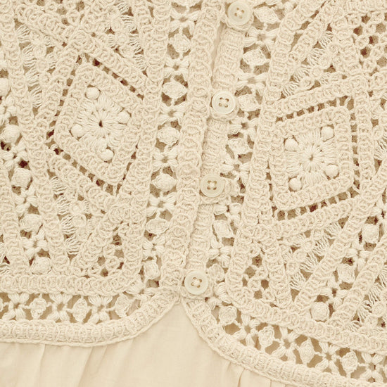 Close-up of a beige lace garment with intricate patterns.