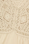 Close-up of a beige lace garment with intricate patterns.