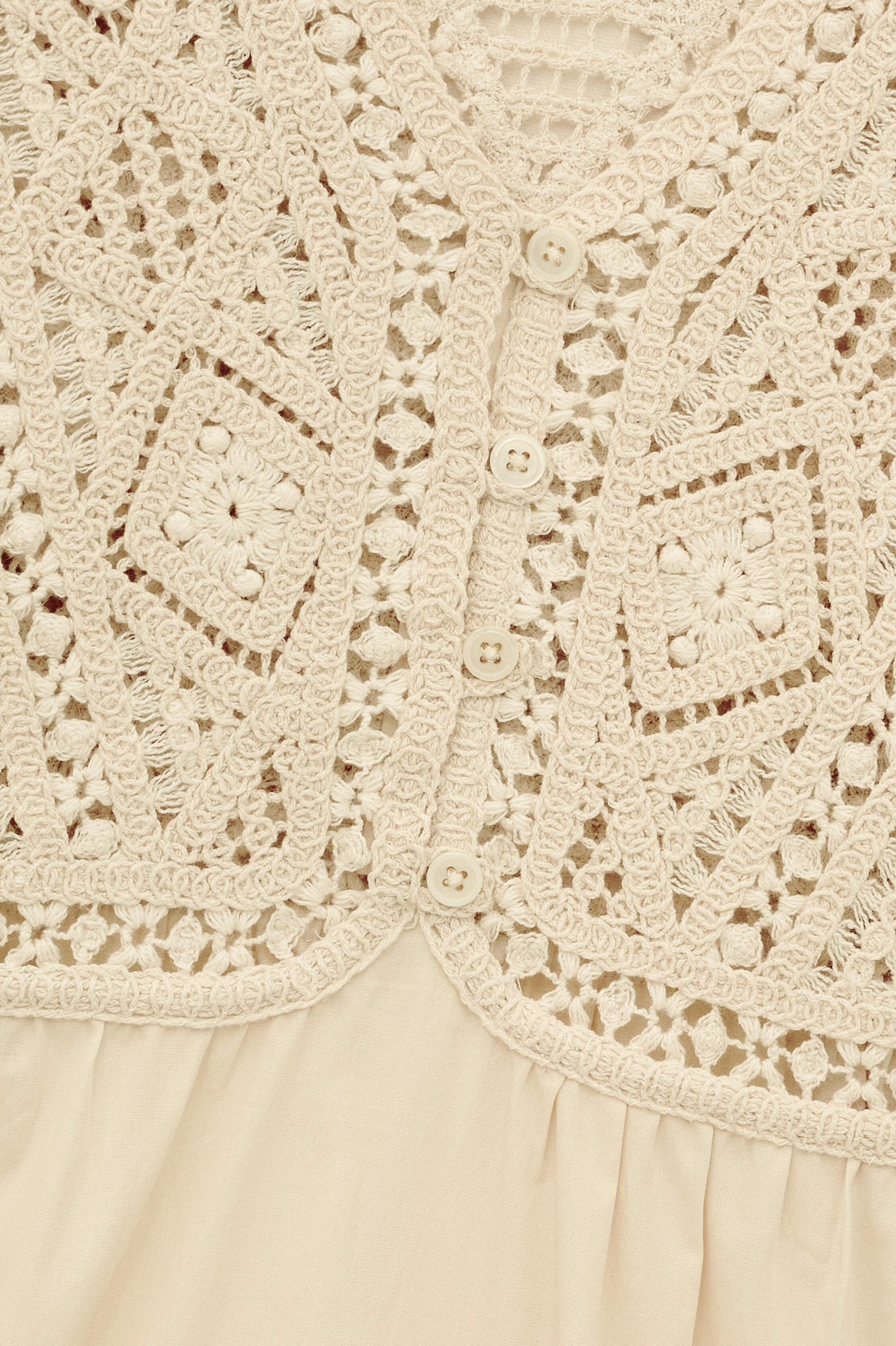 Close-up of a beige lace garment with intricate patterns.