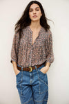 Woman wearing a patterned blouse and blue jeans against a plain background from bash