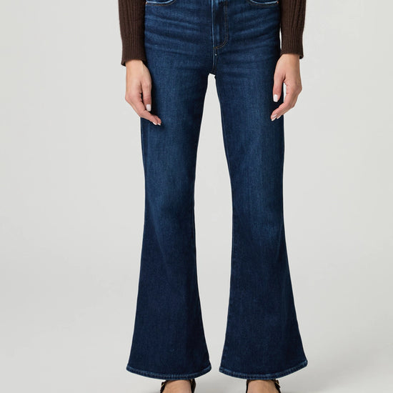 Person wearing blue flared jeans on a plain background from paige