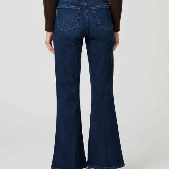 Person wearing blue flared jeans on a plain background rear view