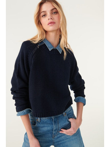 Crew neck short navy jumper with raglan sleeves and a zip fastening at the neck running from the shoulder