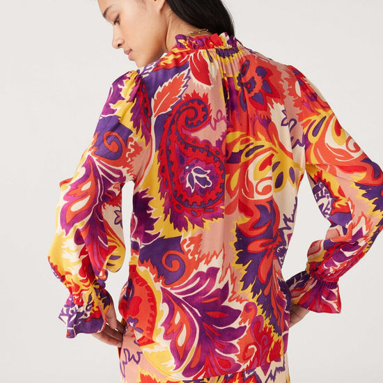 Button through blouse with long sleeves ruffle collar in a vibrant paisley inspired orange yellow and purple print