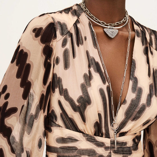 Close-up of a person wearing a patterned dress with layered necklaces.