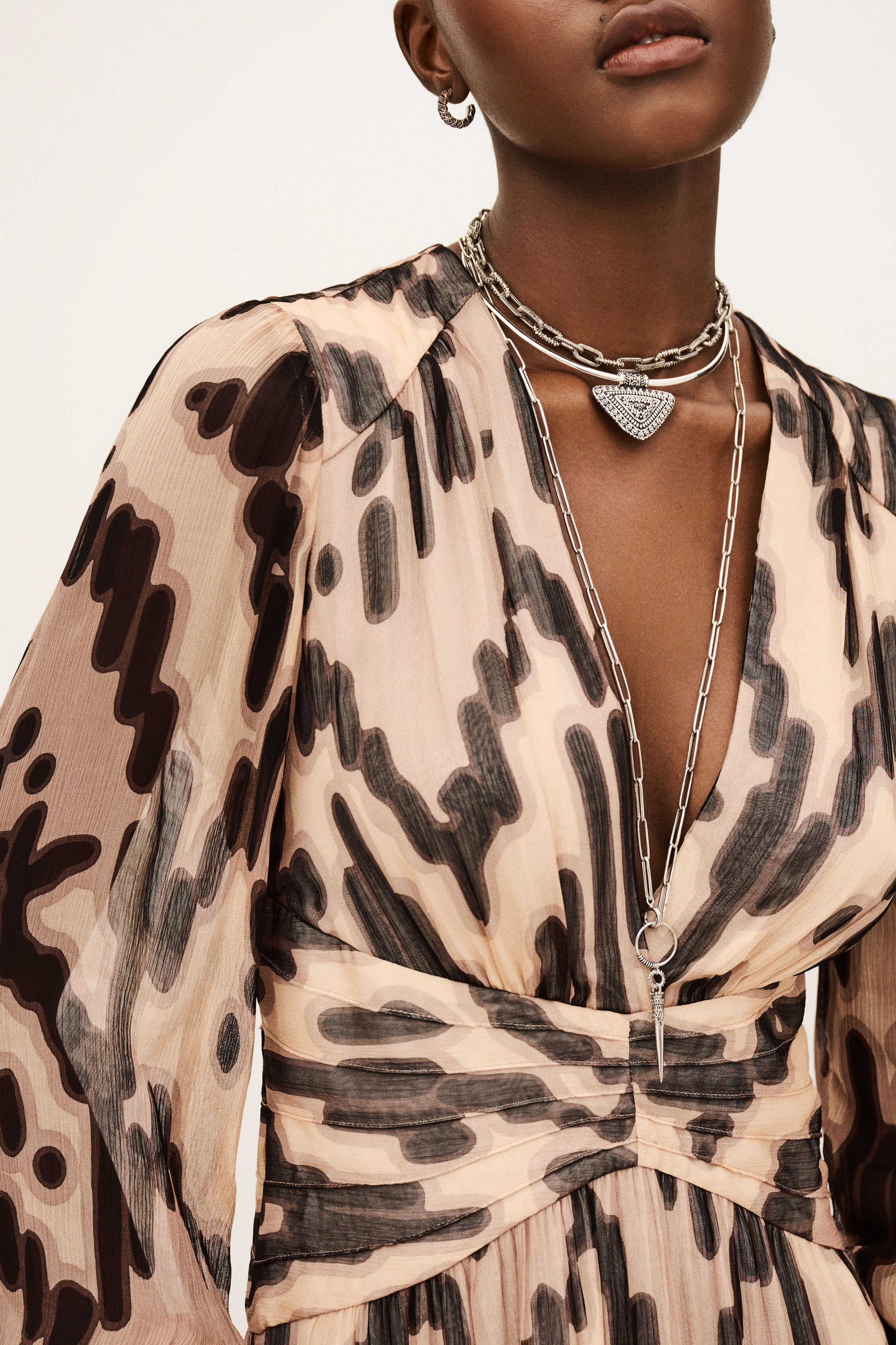 Close-up of a person wearing a patterned dress with layered necklaces.