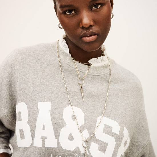 Person wearing a gray sweatshirt with 'BA & SB' text on a plain background