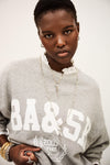 Person wearing a gray sweatshirt with 'BA & SB' text on a plain background