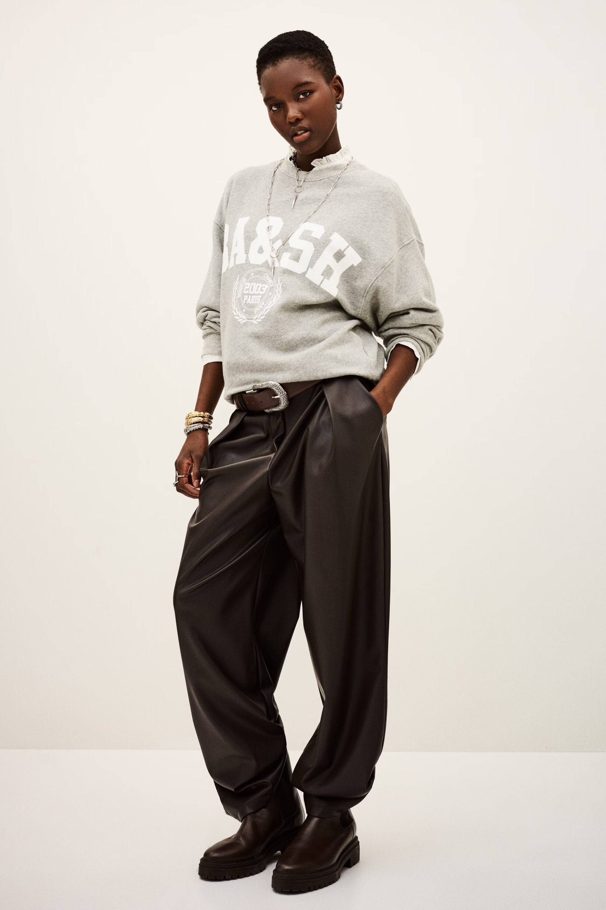 Person wearing a gray sweatshirt with 'A&SR' branding and dark pants on a white background