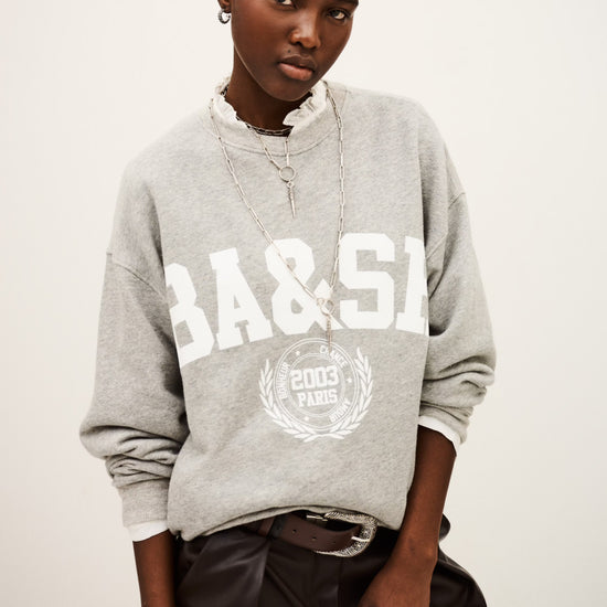 Person wearing a gray sweatshirt with 'BA&SI' branding on a white background