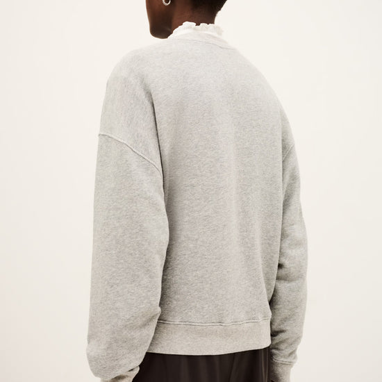 Person wearing a gray sweatshirt from behind on a white background