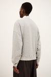 Person wearing a gray sweatshirt from behind on a white background