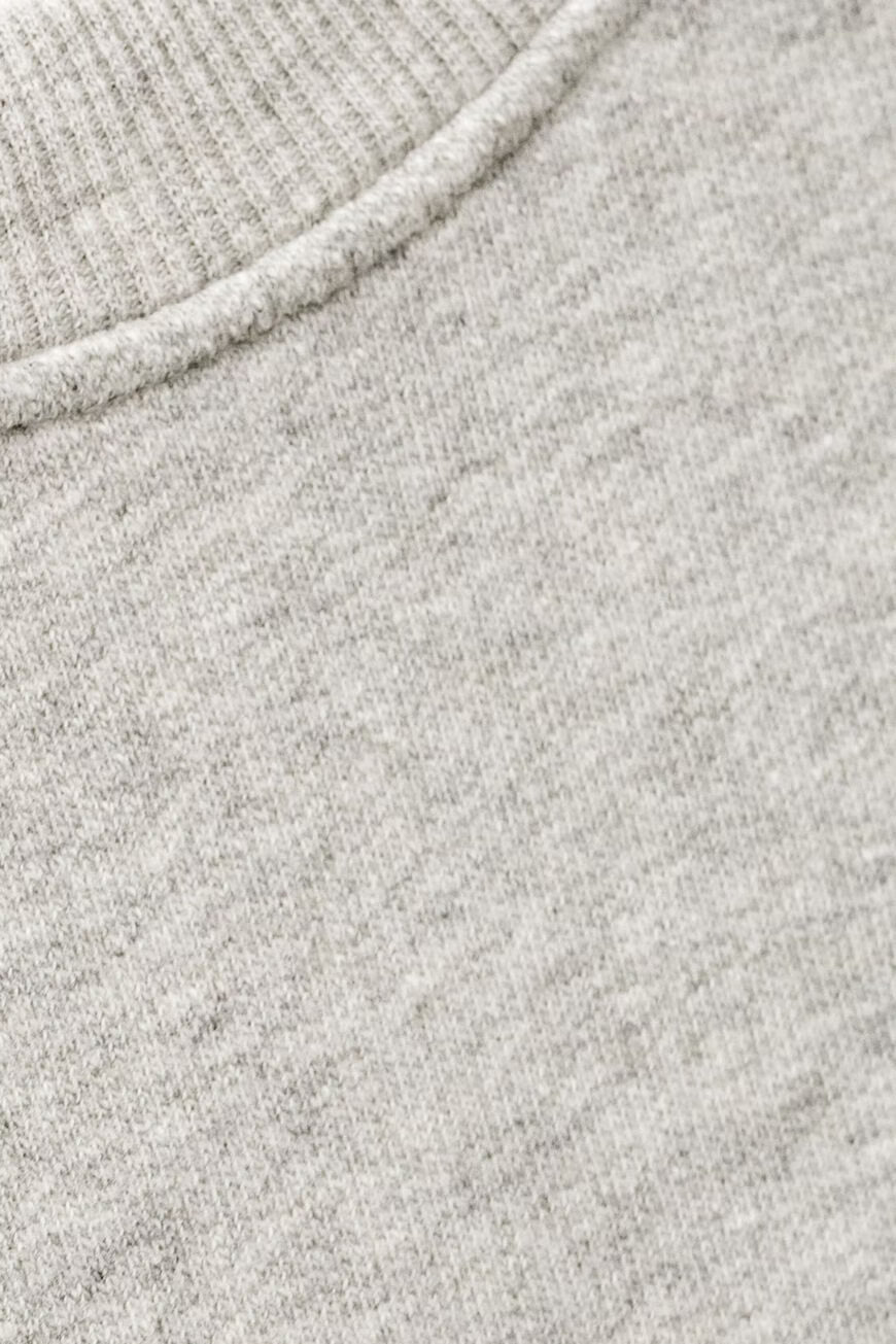 Close-up of a light heather gray knit fabric with a ribbed crew neck collar.