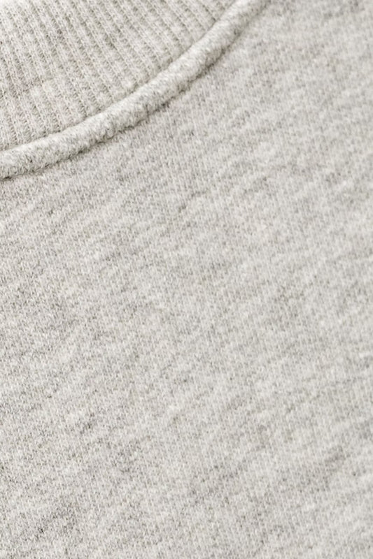 Close-up of a light heather gray knit fabric with a ribbed crew neck collar.