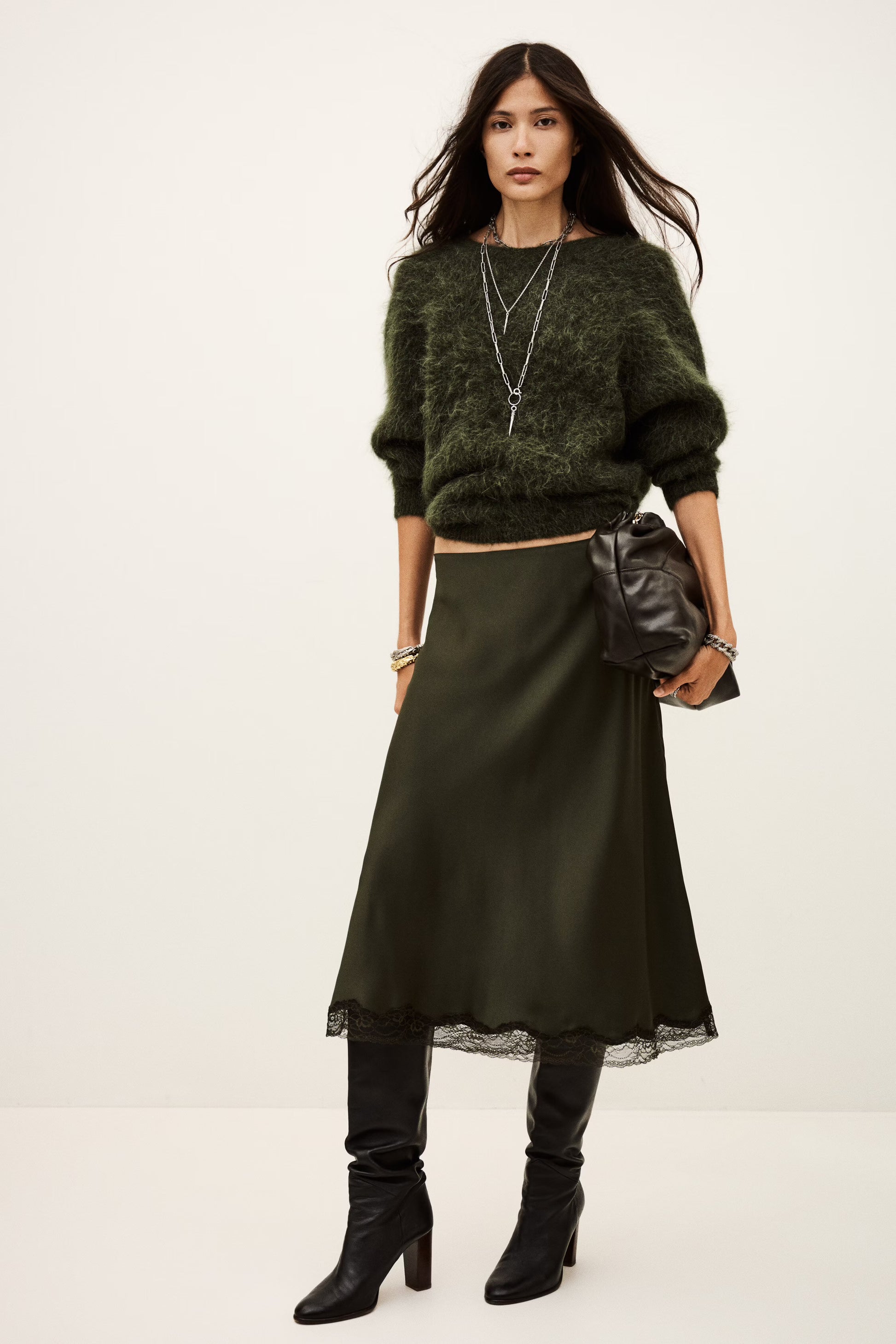 Woman wearing a green sweater, green skirt, and black boots on a white background from Ba&sh