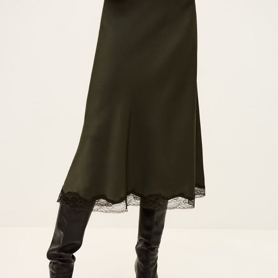 Person wearing a khaki skirt with lace trim and black boots on a white background from ba&sh