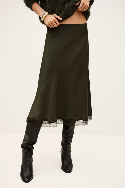 Person wearing a khaki skirt with lace trim and black boots on a white background from ba&sh