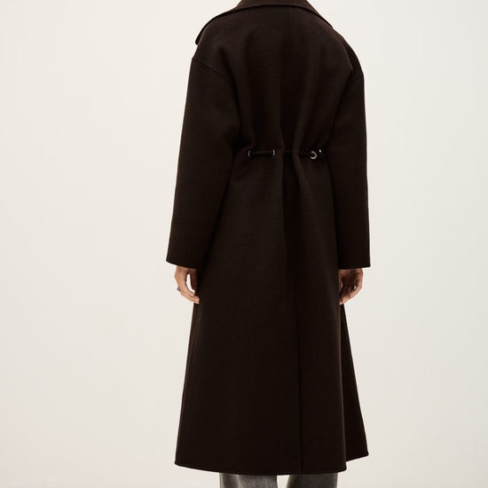 Person wearing a long black coat on a white background rear view