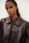 Woman wearing a brown leather coat with a neutral background