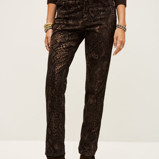 Person wearing dark brown snake print pants and matching top on a white background