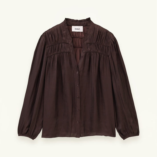 A dark brown long-sleeve blouse with a gathered, smocked bodice and button-front closure, displayed flat against a light cream background.