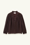 A dark brown long-sleeve blouse with a gathered, smocked bodice and button-front closure, displayed flat against a light cream background.