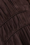 Close-up of a dark brown pleated fabric garment with gathered seams and a smooth satin-like finish.
