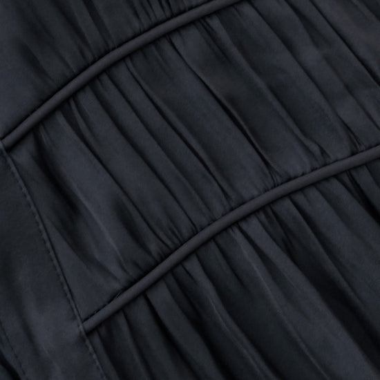 Close-up of a dark charcoal gray pleated fabric with curved seam lines.