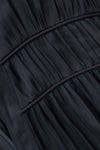 Close-up of a dark charcoal gray pleated fabric with curved seam lines.