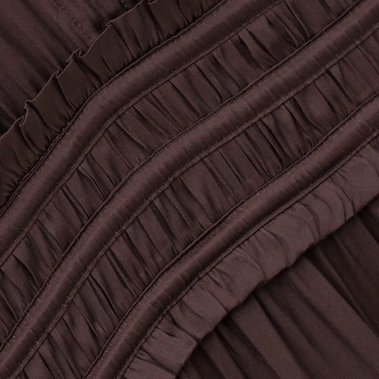 Close-up of a dark brown pleated fabric with horizontal ruffled trim and gathered seams.