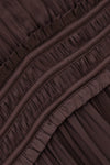 Close-up of a dark brown pleated fabric with horizontal ruffled trim and gathered seams.