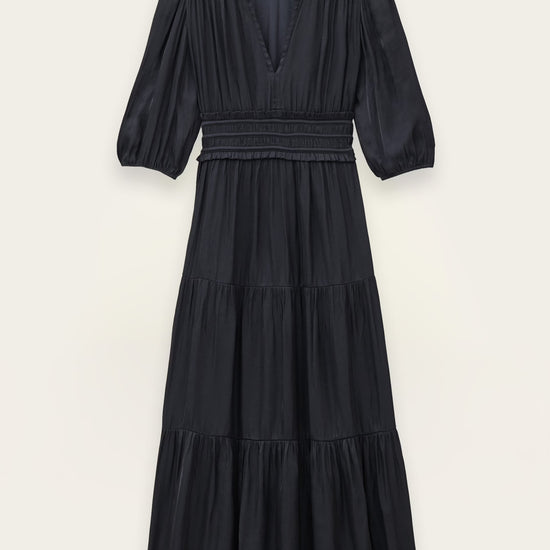 A black tiered midi dress with three-quarter sleeves and a smocked waist, shown flat against a light beige background.