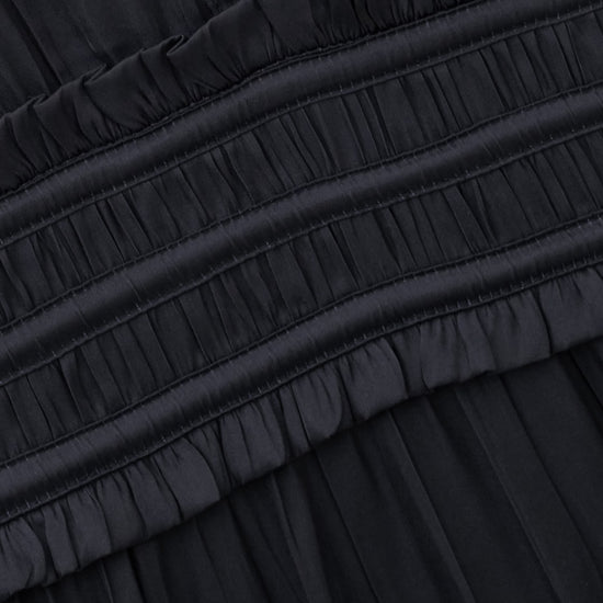 Close-up of a black pleated fabric garment with a gathered elastic waistband and ruffled trim.