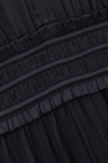 Close-up of a black pleated fabric garment with a gathered elastic waistband and ruffled trim.