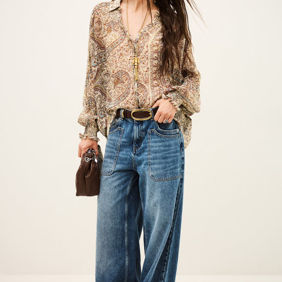 woman wearing paisley blue and brown shirt and jeans on white background full outfit shot