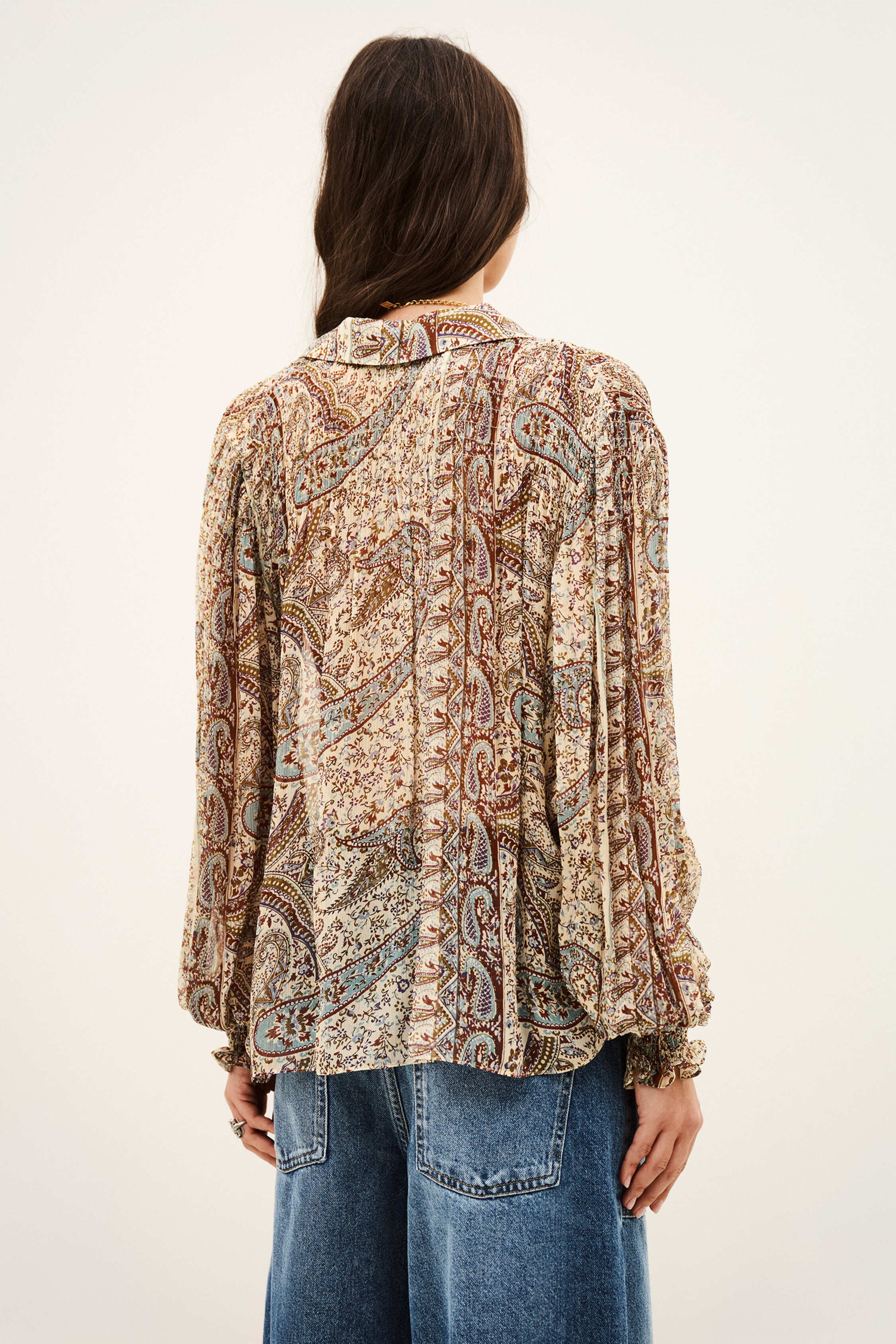 woman wearing paisley blue and brown shirt and jeans on white background rear view
