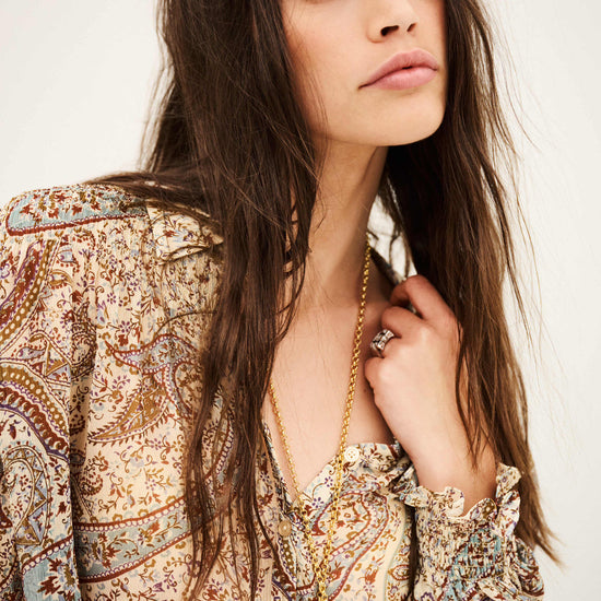 woman wearing paisley blue and brown shirt close up on white background