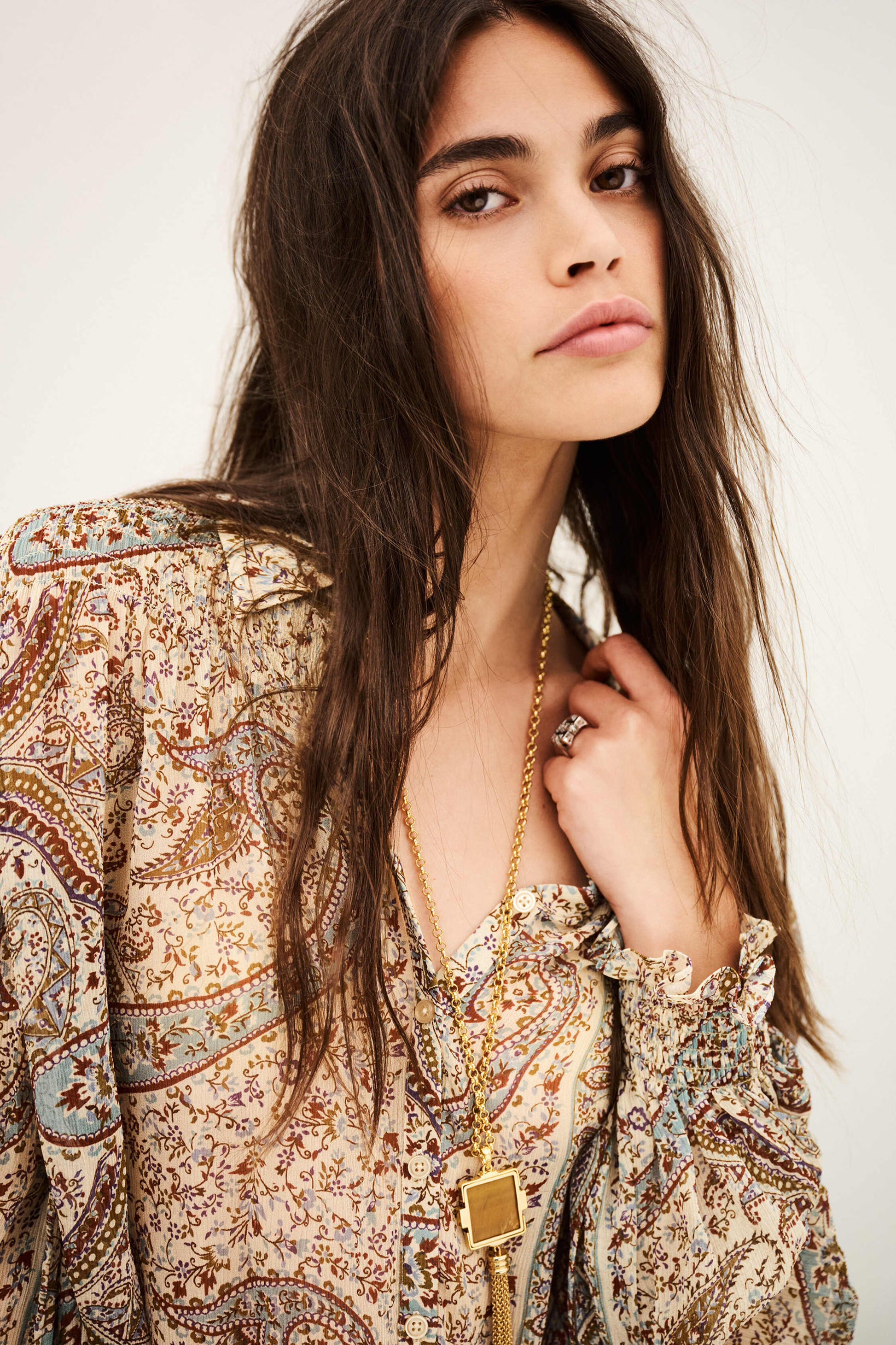 woman wearing paisley blue and brown shirt close up on white background