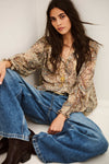 woman wearing paisley blue and brown shirt and jeans on white background sat down