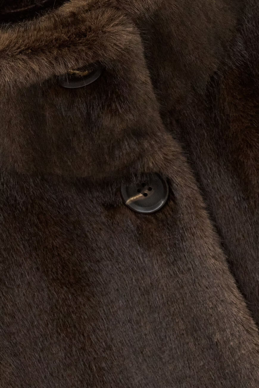 Close-up of a dark brown fur or faux-fur garment with a button closure and soft textured surface.