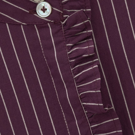 Close-up of a dark purple and white vertically striped ruffled blouse with decorative buttons.