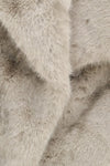 A close-up of plush faux fur fabric in a light warm gray or greige tone, showing the soft texture and layered folds of the material.