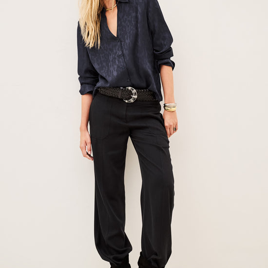 Woman wearing blue shirt and black trousers on white background