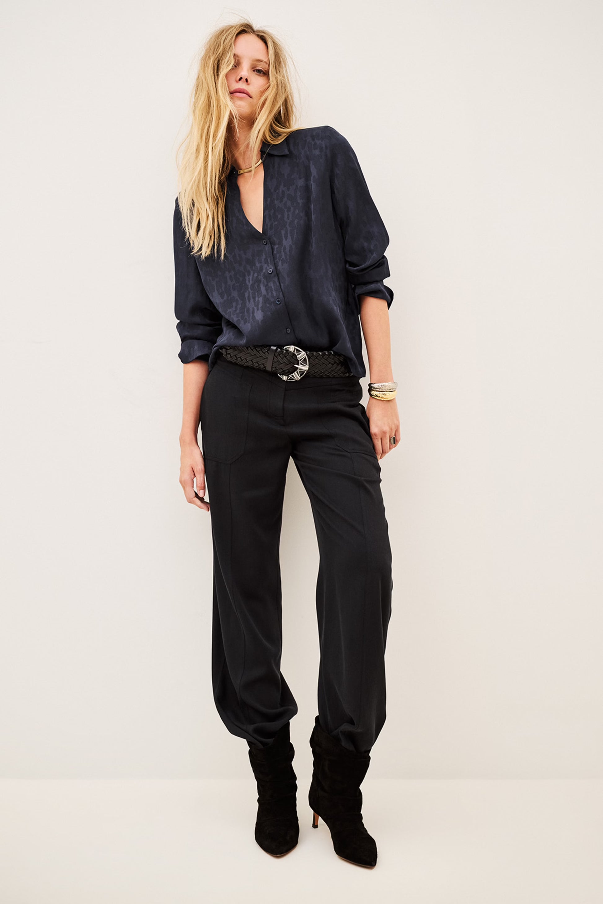 Woman wearing blue shirt and black trousers on white background