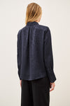 Woman wearing blue shirt and black trousers on white background rear view
